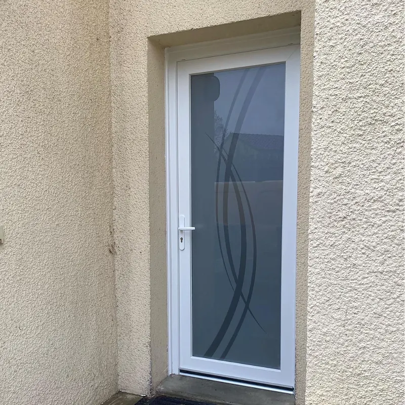 Porte d’entrée PVC blanche avec vitrage dépoli à motif de courbes, sur une façade crépie